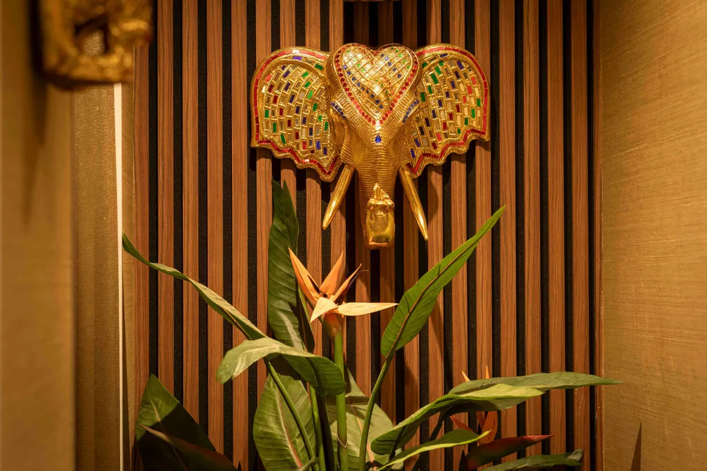 Gouden olifantenkop met gekleurd spiegelglas boven een paradijsvogelbloem
